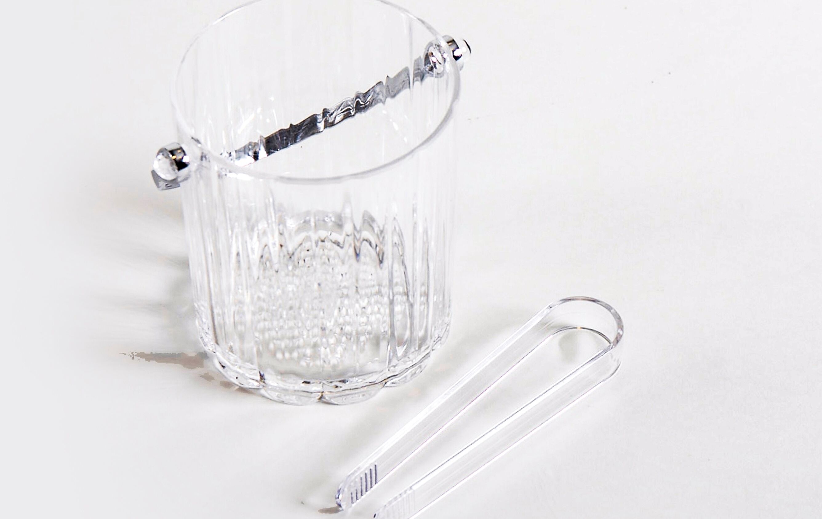 A clear glass mug with a handle and a clear plastic spoon beside it.