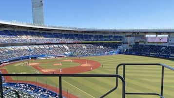 Un estadio con varios niveles de asientos, un campo de béisbol y un edificio alto al fondo.