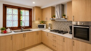 A modern kitchen with wooden cabinets, a stainless steel range hood, a microwave, a gas stove, and a built-in oven. - Luxury 6BR Villa / Pool /Walk to Beach (Punta Cana)