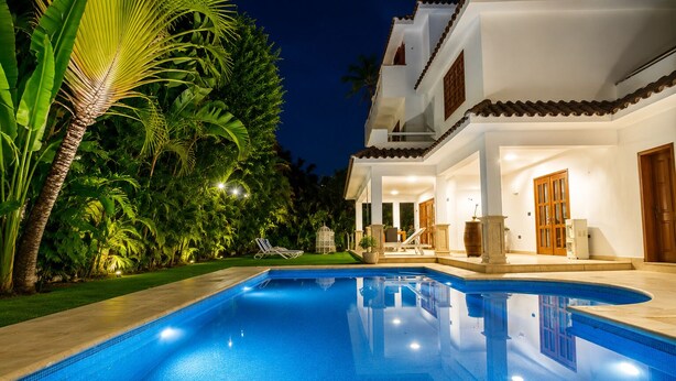 A swimming pool with a white house in the background, surrounded by greenery. - Luxury 6BR Villa / Pool /Walk to Beach (Punta Cana)