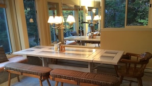 Un espace repas avec une grande table, des bancs et un lustre.