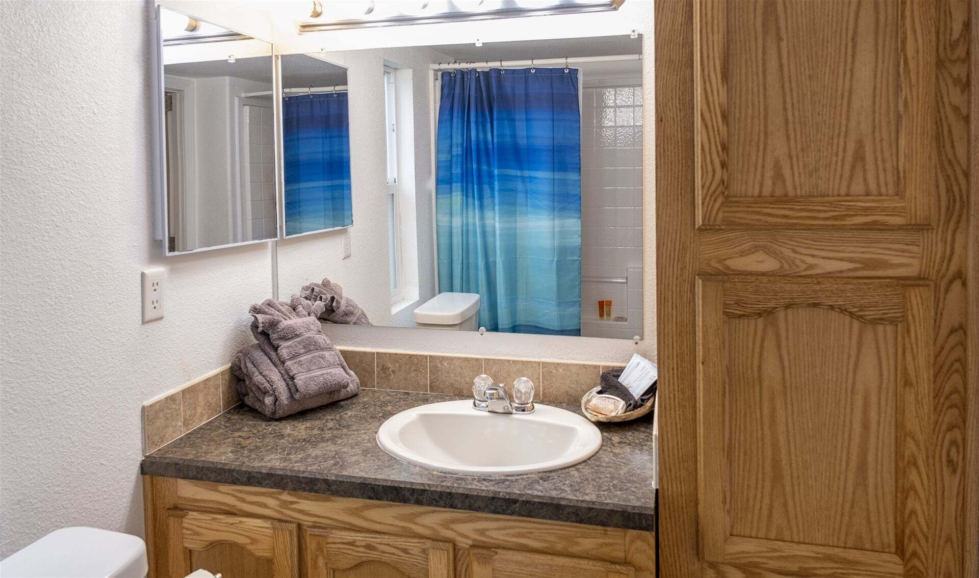 A bathroom with a wooden vanity, a sink, a mirror, and a shower curtain.