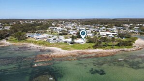 Vue aérienne d’une zone résidentielle côtière, avec des maisons, une plage et une eau cristalline.