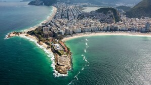 An aerial view of a coastal city with a densely packed urban area, a long beachfront, and a prominent mountain in the background. - Studio Lily1 - Coração do Rio (Laranjeiras)