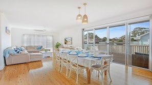 Relax in this spacious living area with a large dining table for six, a comfortable sofa, and a stunning view of the surrounding landscape.