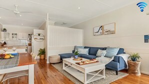 Un salon moderne avec un canapé bleu, une table basse blanche et un coin repas comprenant une table et des chaises en bois.