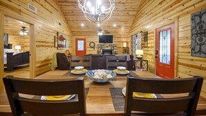 A cozy log cabin interior with a dining area, a living room, and a fireplace. - Shear Pleasure|Romantic|Farmhouse Style (Hochatown)