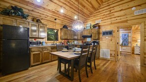 A wooden cabin interior with a kitchen, dining area, and a living space. - Shear Pleasure|Romantic|Farmhouse Style (Hochatown)