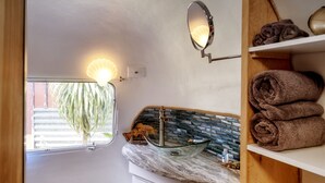 A bathroom with a glass sink, a mirror, and a shelf with towels. - Cowabunga - A luxury Airstream trailer just minutes from our private dock in the harbor and beach (Fort Bragg)