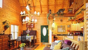 Un intérieur de chalet chaleureux avec un coin repas, un canapé et une cuisine.