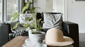 Un salon moderne avec un canapé en cuir noir, une table basse en bois et une grande fenêtre.