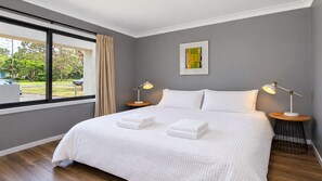 Un dormitorio moderno con una cama grande, dos mesitas de noche, una ventana con cortinas y un cuadro en la pared.