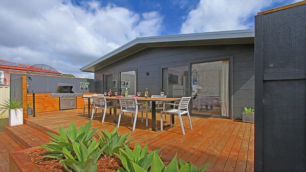 Una casa moderna con terraza, parilla y zona de comedor con sillas y mesa.