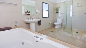 Une salle de bain moderne avec une grande baignoire, un lavabo, des toilettes et une douche à parois de verre.