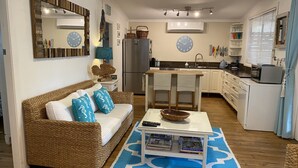 A cozy living room with a wicker sofa, a coffee table, and a blue patterned rug. - The Beach House - close to everything! (Patonga)