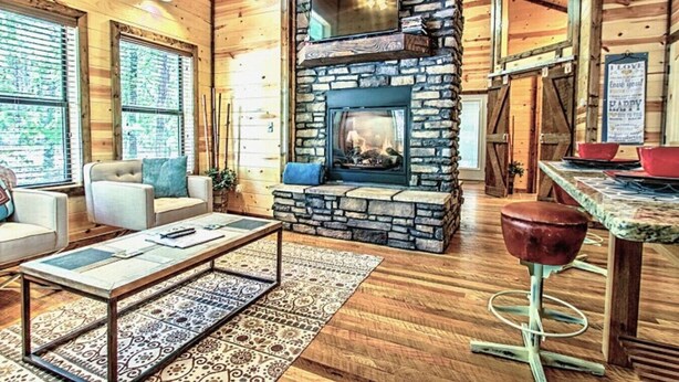 Una sala de estar acogedora con chimenea de piedra, paredes de madera y una zona de estar confortable.