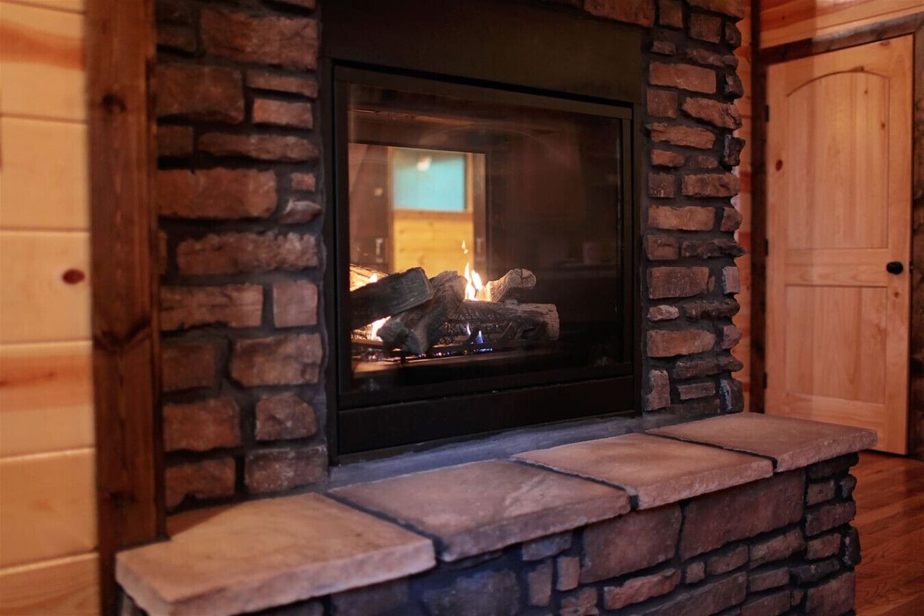 A fireplace with a stone surround and a wooden door in the background.