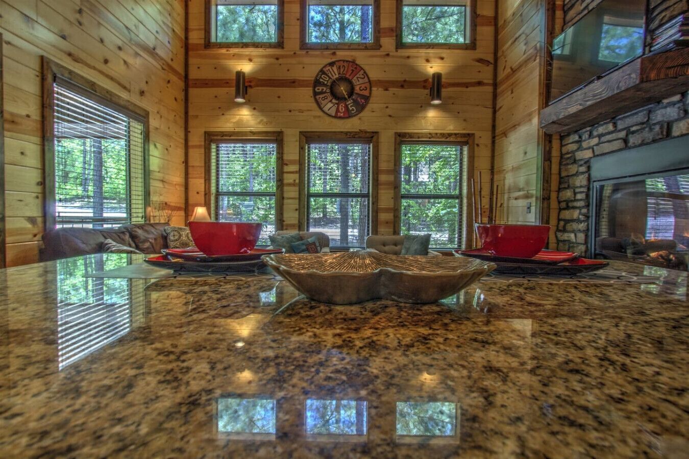 A spacious kitchen with granite countertops, a central island, and a large window overlooking a forest.