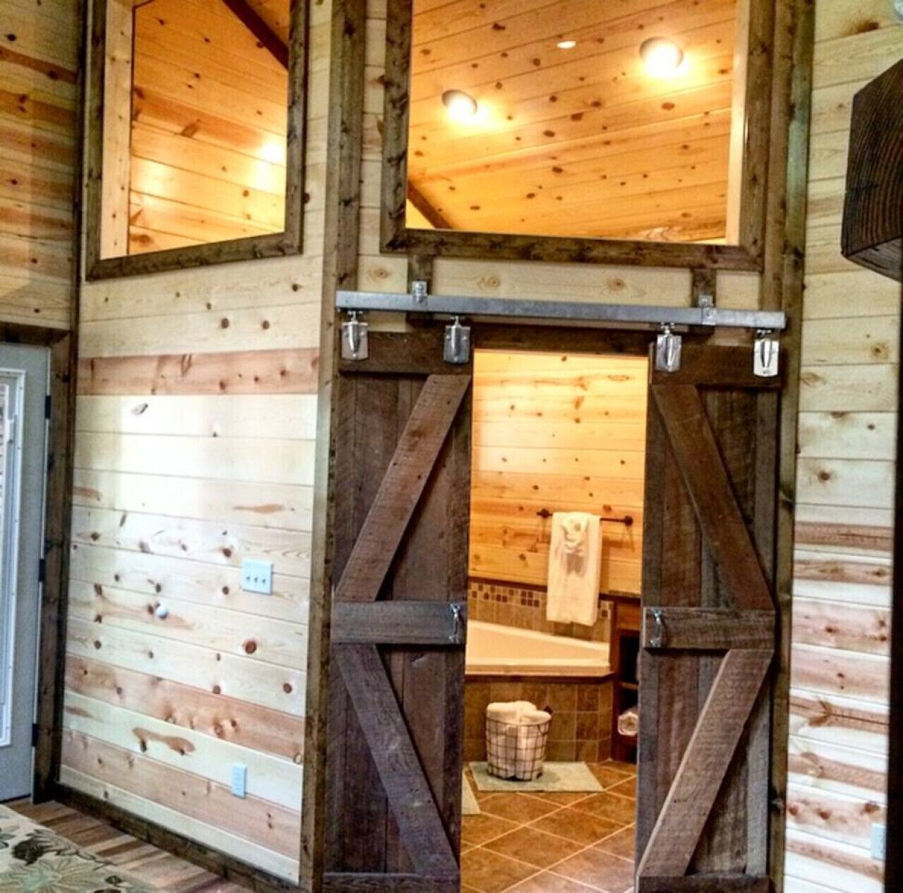 A rustic wooden cabin interior with a large sliding door leading to a bathroom.