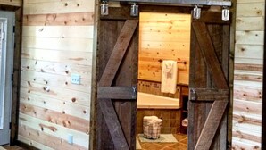 Interior rústico de una cabaña de madera con un amplio acceso corredizo a un baño.
