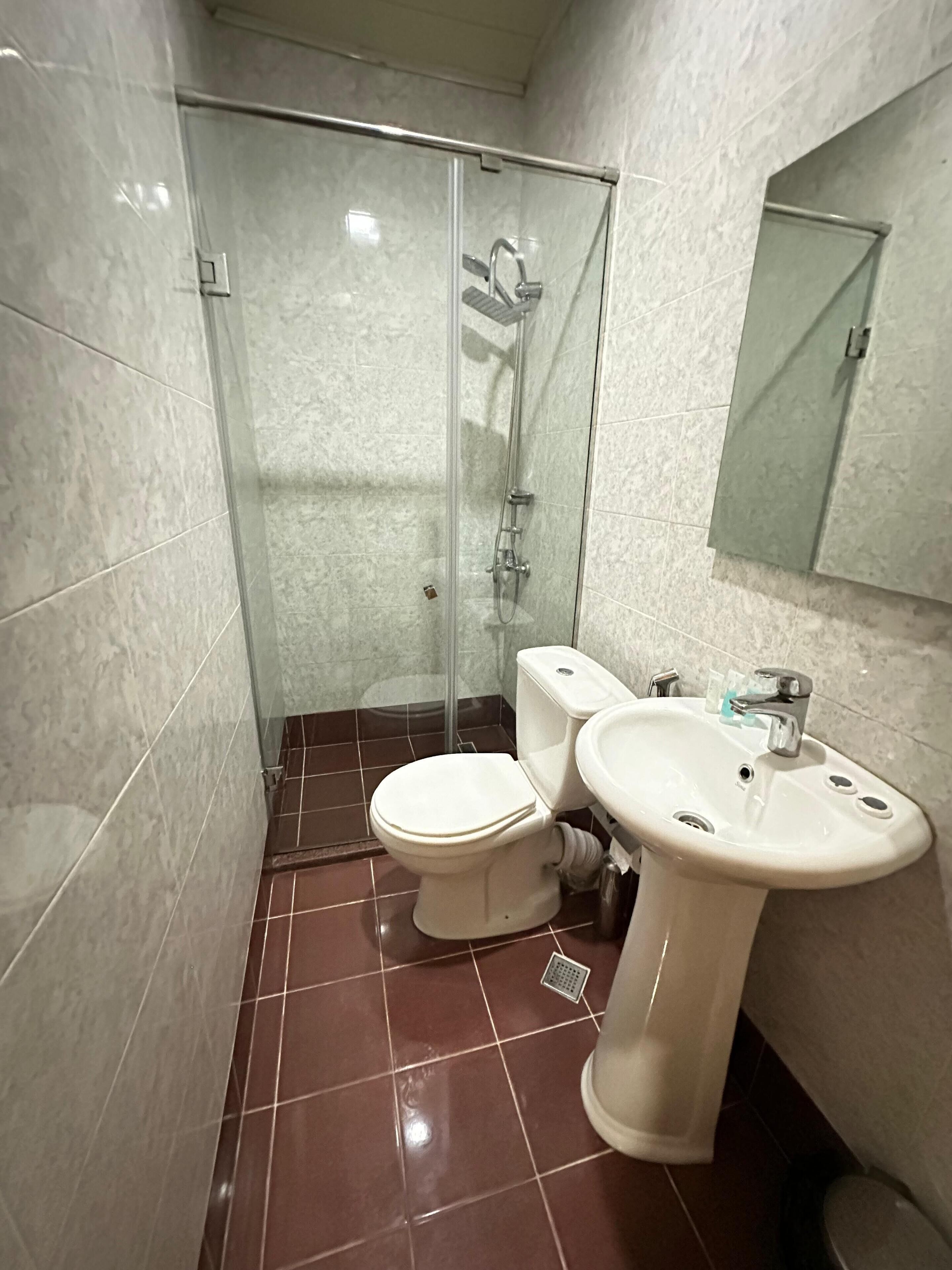 A bathroom with a glass-enclosed shower, a toilet, and a sink.