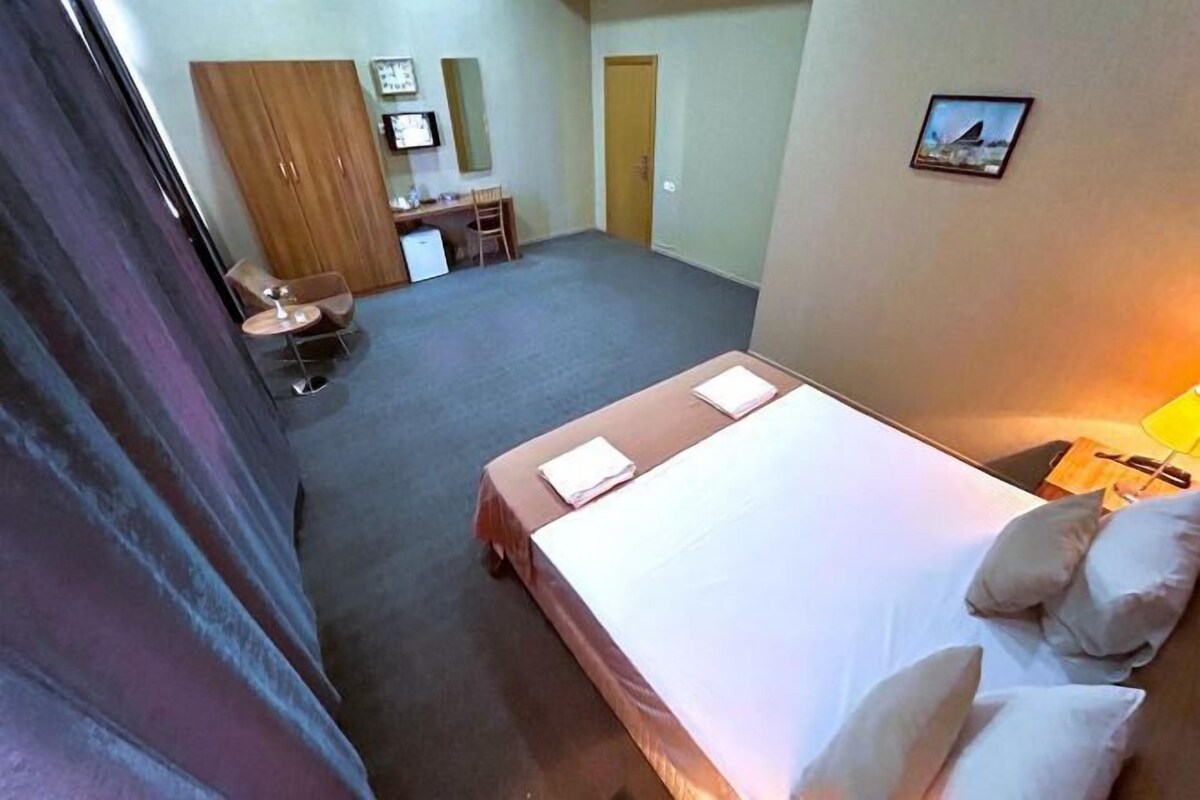A bedroom with a bed, a desk, a chair, and a wardrobe.