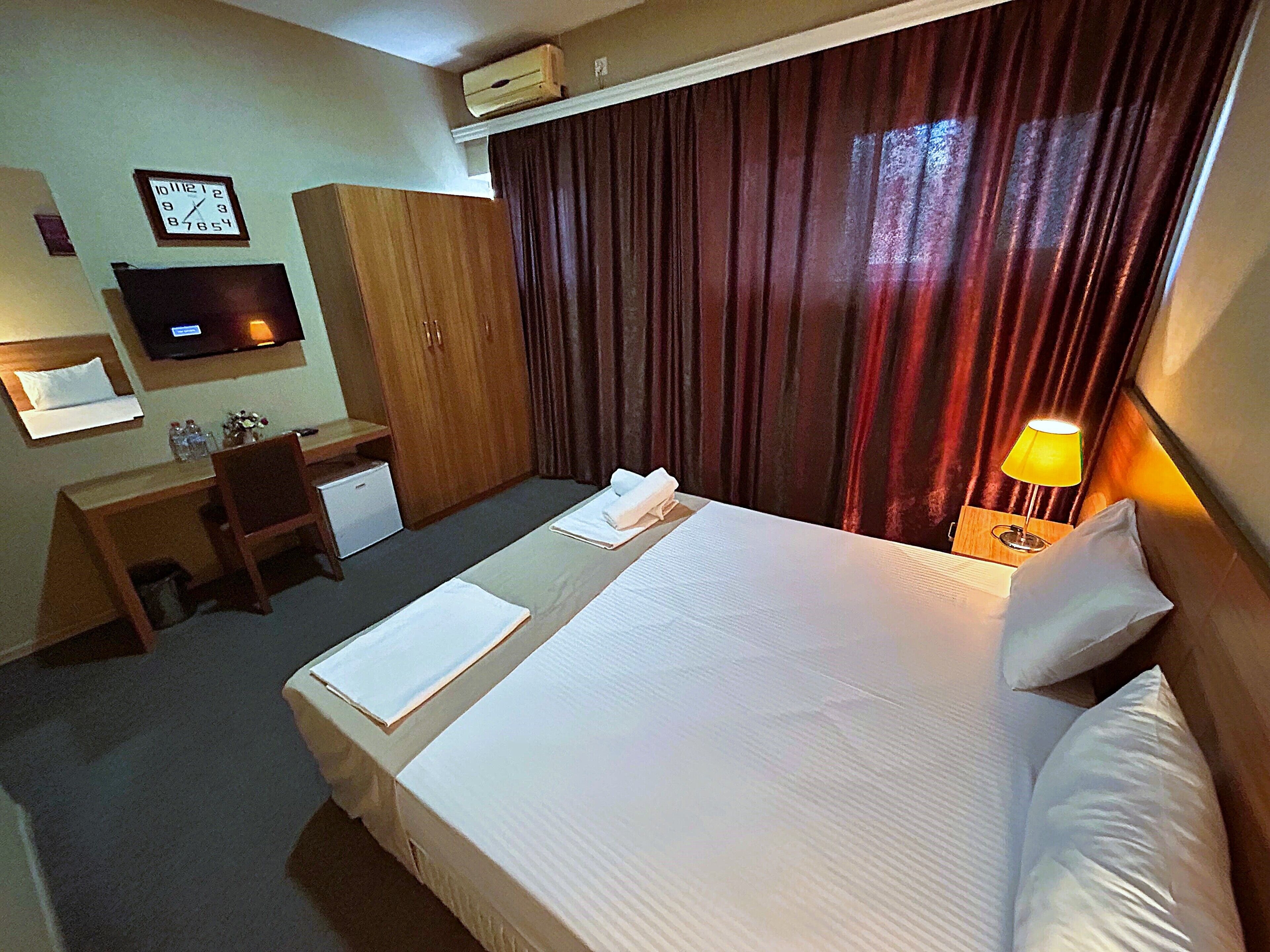A hotel room with a bed, a desk, a television, and a wardrobe.