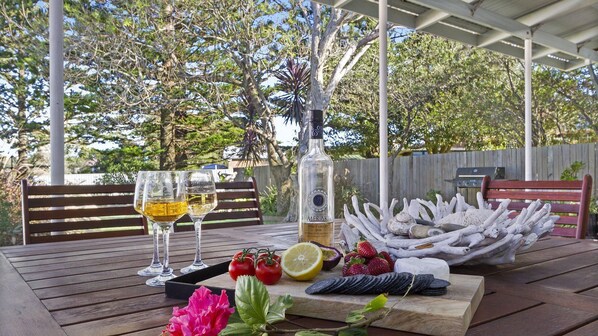 A wooden table with two wine glasses, a bottle of Meraki Pinot Grigio 2018, and a variety of fruits and vegetables.