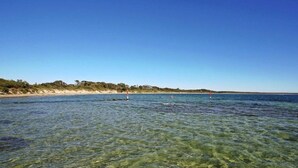 Klarer Blick auf die Küste mit Sandstrand und ruhigem Wasser.