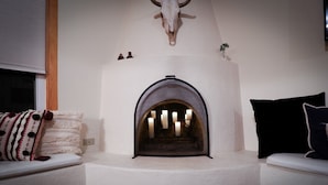 Una habitación acogedora con chimenea, una decoración de cráneo de vaca y un banco con cojines.