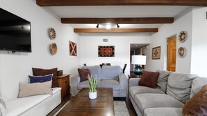 Una sala de estar con un sofá, una mesa de centro y un televisor en la pared.