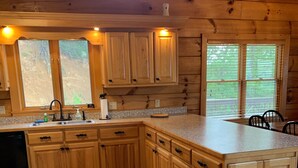 A wooden cabin kitchen with a granite countertop, wooden cabinets, and a built-in dishwasher. - Breathtaking mountain and sunset views...huge cabin with cozy atmosphere (Pigeon Forge)