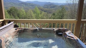 A hot tub with a wooden deck and a scenic mountain view. - Breathtaking mountain and sunset views...huge cabin with cozy atmosphere (Pigeon Forge)