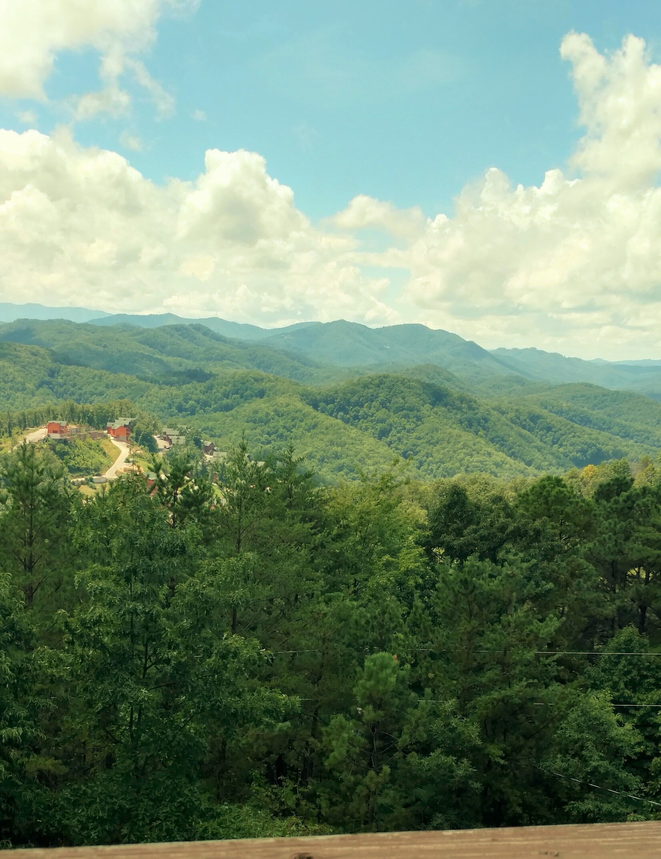 Un paysage montagneux, avec une forêt dense et une route sinueuse menant à un petit village.
