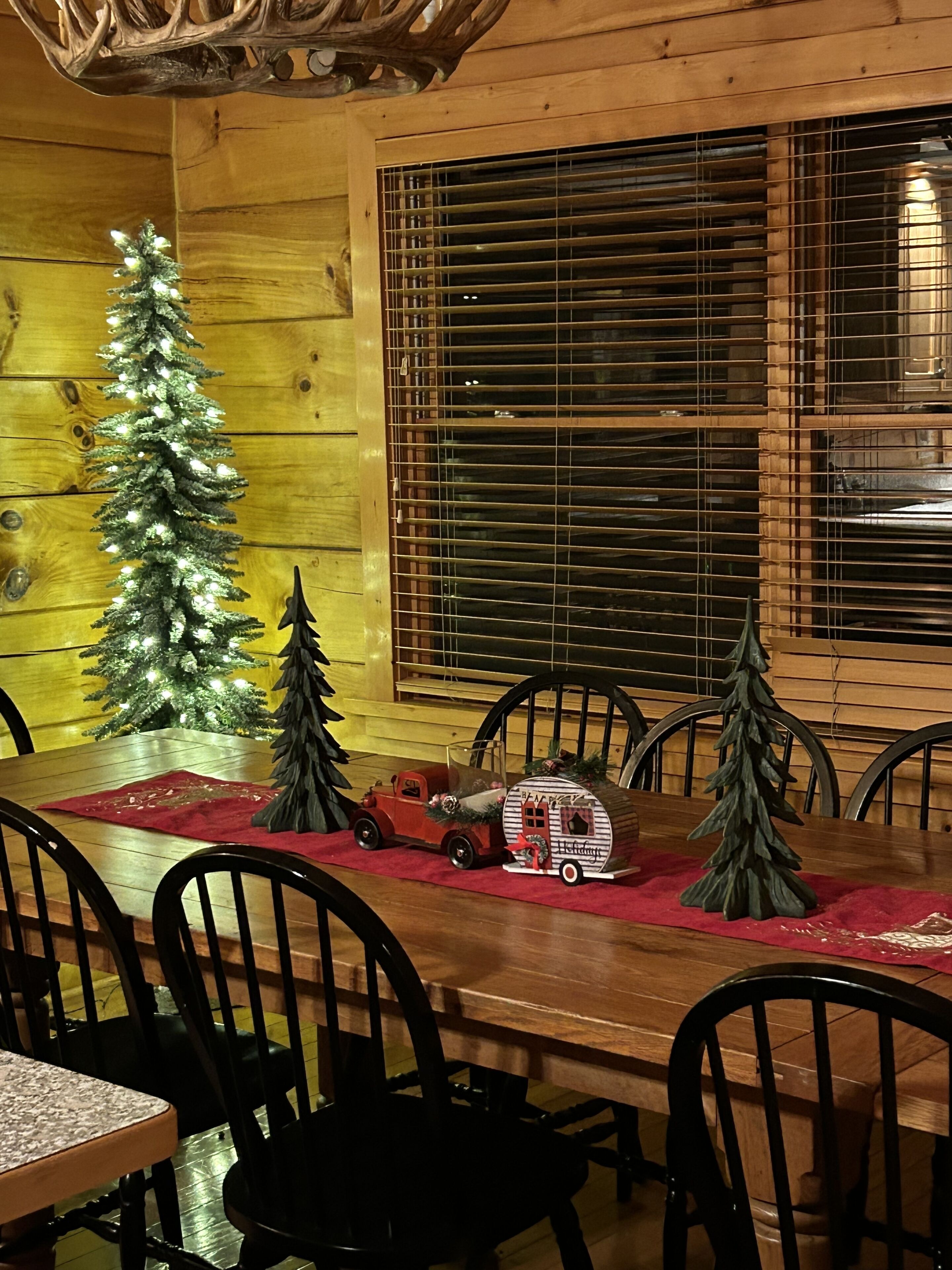 Ein Esszimmer mit Holzboden, gedecktem Tisch für vier Personen, einem Weihnachtsbaum und einem dekorativen Schlitten.