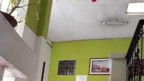 Uma escada com uma parede verde, uma janela com grades e um quadro emoldurado na parede.