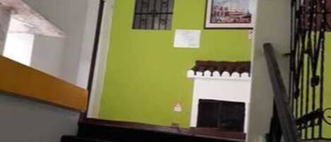 A staircase with a green wall, a window with bars, and a framed picture on the wall.