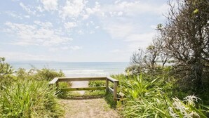 A wooden pathway leading to a beach with a clear view of the ocean.