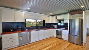A modern kitchen with white cabinets, stainless steel appliances, and a wooden countertop.
