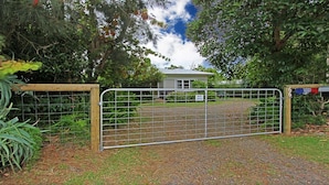 A gated property with a gravel driveway leading to a house. - Culburra Sands – cosy cottage (Culburra Beach)