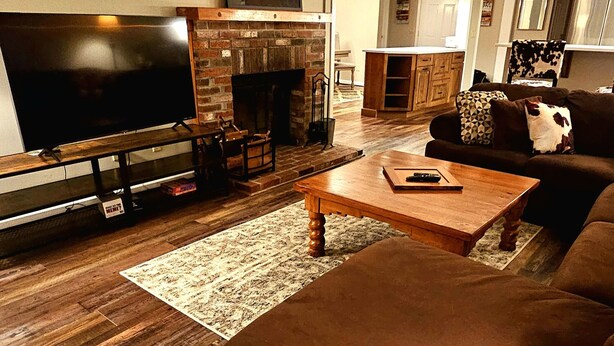 A living room with a TV, fireplace, sofa, and wooden flooring. - Mount Snow Mountain Views - Spacious and Clean 4 Bedrooms 3 Baths Condo  (West Dover)