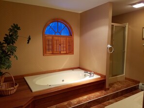 A bathroom with a large bathtub, a wooden vanity, a shower, and a window with shutters. - Mount Snow Mountain Views - Spacious and Clean 4 Bedrooms 3 Baths Condo  (West Dover)
