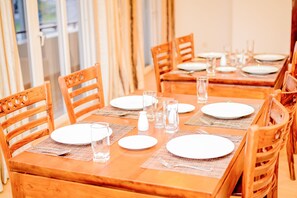 A dining table set with plates, glasses, and cutlery, surrounded by wooden chairs. - Shamaz Galle (Galle)