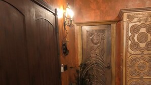 Una habitación con piso de madera, un armario grande, una puerta decorativa y una lámpara fijada a la pared.