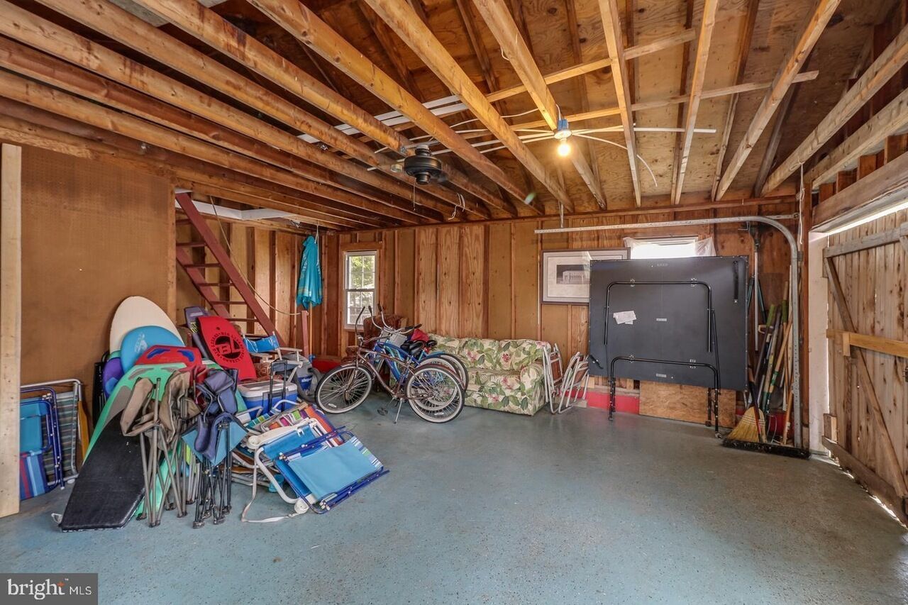 Eine Garage mit Holzbalkendecke, einem Fahrrad, einer Couch und verschiedenen Sportgeräten.