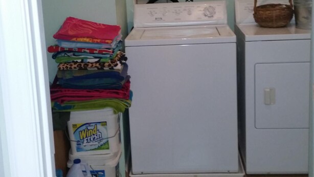 A laundry area with a washing machine, a dryer, and a stack of folded clothes. - Bethany's Hidden Treasure and Hide Away 4Br that Sleeps 12 w/Game Room in Garage (Ocean View)