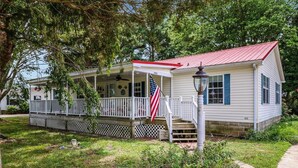 Une maison de plain-pied avec un toit rouge, une véranda et un drapeau américain.