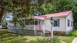 Une maison de plain-pied avec un toit rouge, une véranda et un drapeau américain.
