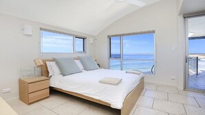 Une chambre à coucher avec un lit, des tables de chevet et une vue sur la mer.