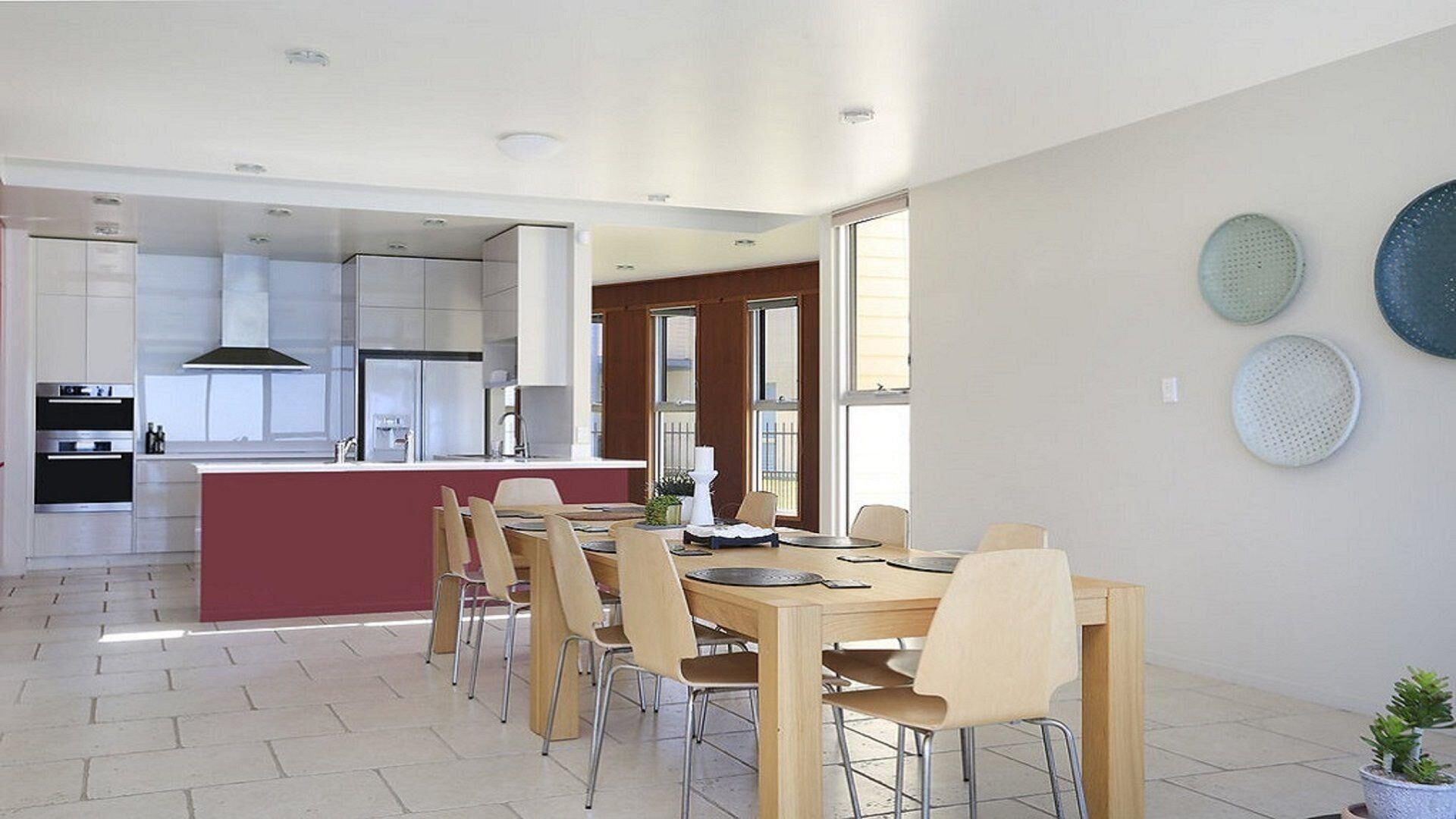 Een moderne keuken met witte kastjes, een centraal eiland en een eethoek met een houten tafel en stoelen.